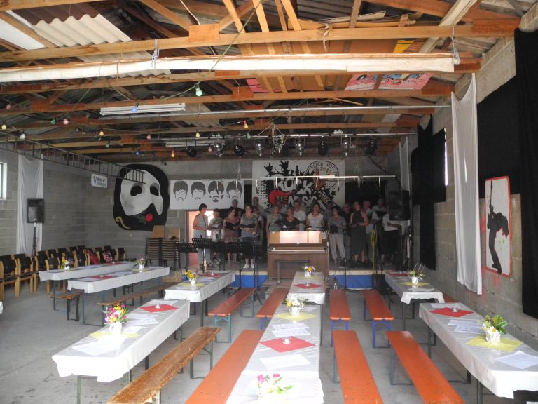 Halle mit Festzeltbänken, geschmückt, Chor steht auf der Bühne, keine Gäste